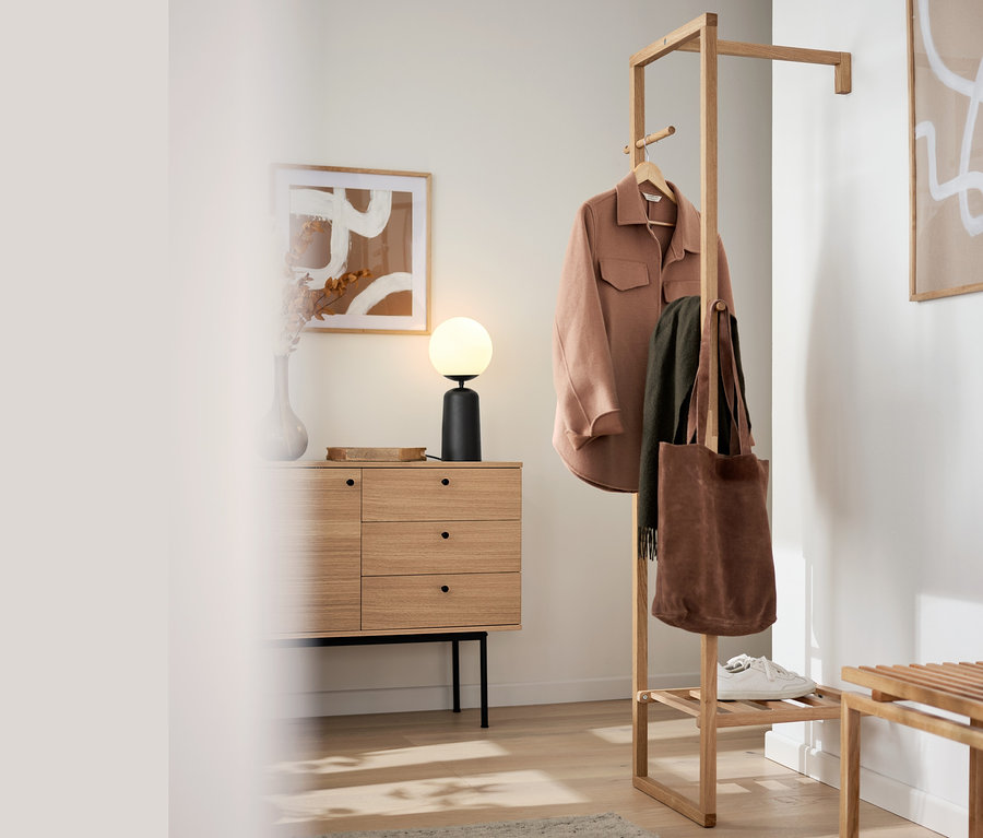 En intérieur, console »Finnsbo« avec tiroirs, un porte-manteau et une lampe de table avec globe en verre.