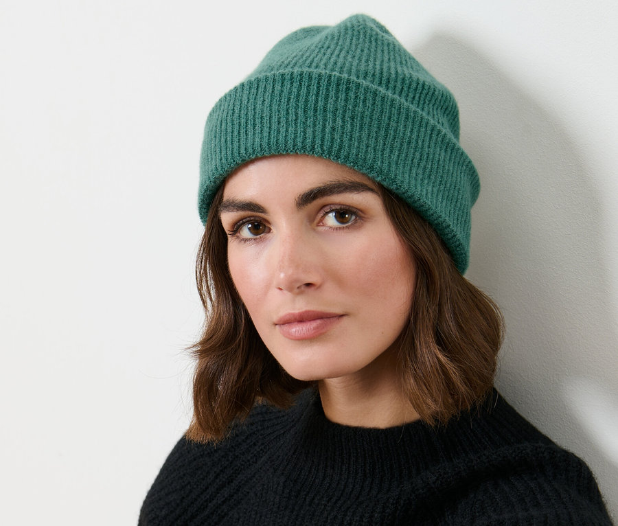 Femme portant un bonnet en maille vert.