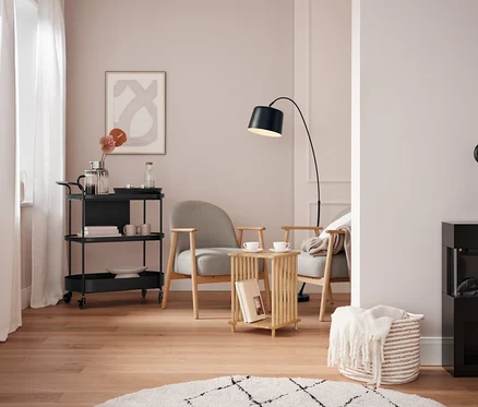 Salon avec un chariot de service noir, deux fauteuils gris et une cheminée noire.
