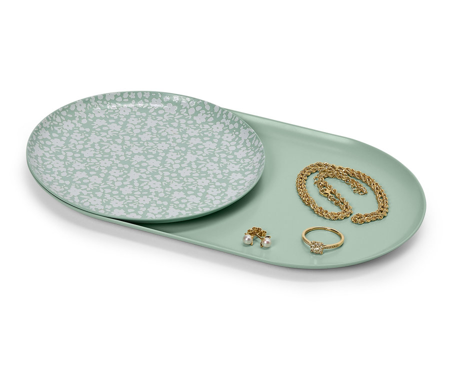 Assiette à motif floral et bijoux en or sur un plateau.