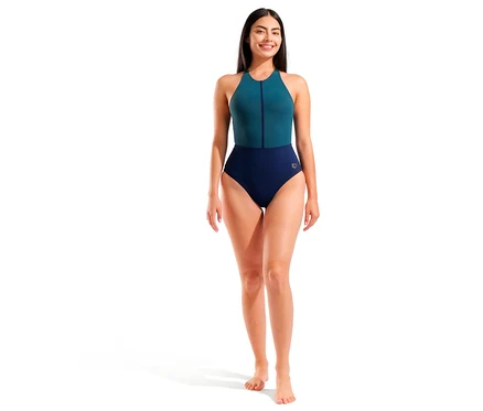 Femme souriante debout, portant un maillot de bain pour femme arena Shapewear Silvia B-Cup Cross Back. Le maillot de bain une pièce est turquoise en haut avec une fermeture éclair et bleu marine en bas.