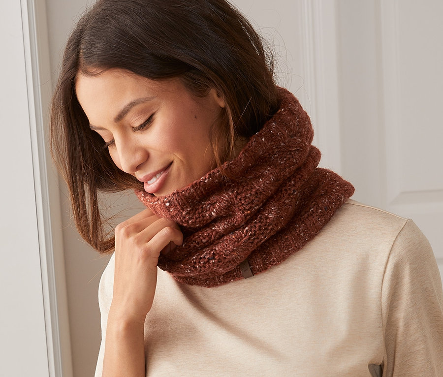 Femme ajustant une écharpe tube en maille autour de son cou.