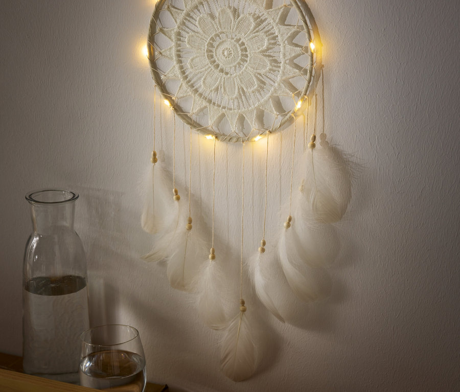 Un attrape-rêves à éclairage LED est accroché au mur, avec une carafe et un verre d'eau en dessous.