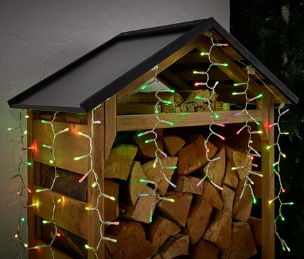 Un abri à bois rempli de bûches, décoré de lumières colorées.