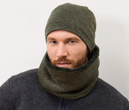 Un homme portant une écharpe-tube en polaire tricotée kaki et un bonnet tricoté assorti.