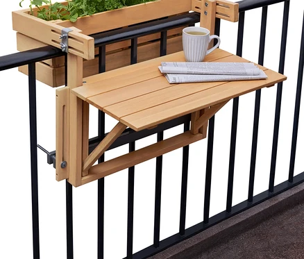 Une jardinière avec des herbes aromatiques et une table pliante avec un journal et une tasse sont suspendues à une balustrade de balcon noire.