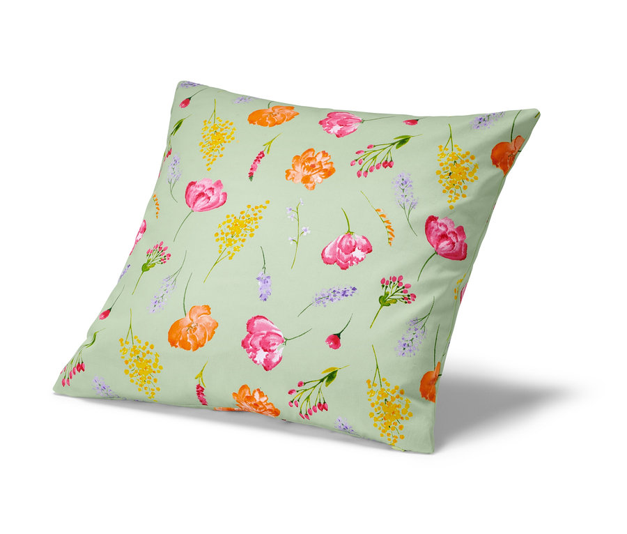 Une housse de coussin décorative à motif floral sur un fond vert clair.