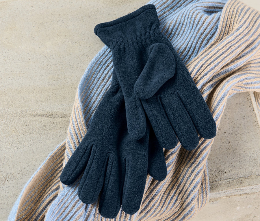 Une paire de gants en polaire repose sur une écharpe.