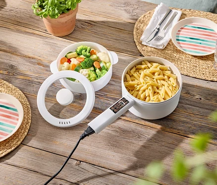 Sur une table en bois, un bol de légumes, un bol de pâtes et des assiettes sur des sets de table.