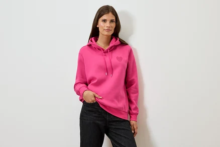 Femme portant un sweat à capuche rose et un jean noir.