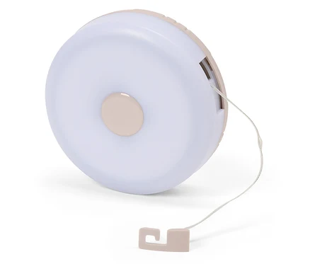 Gros plan d'une lampe de chevet ronde rose clair avec cordon sur fond blanc.