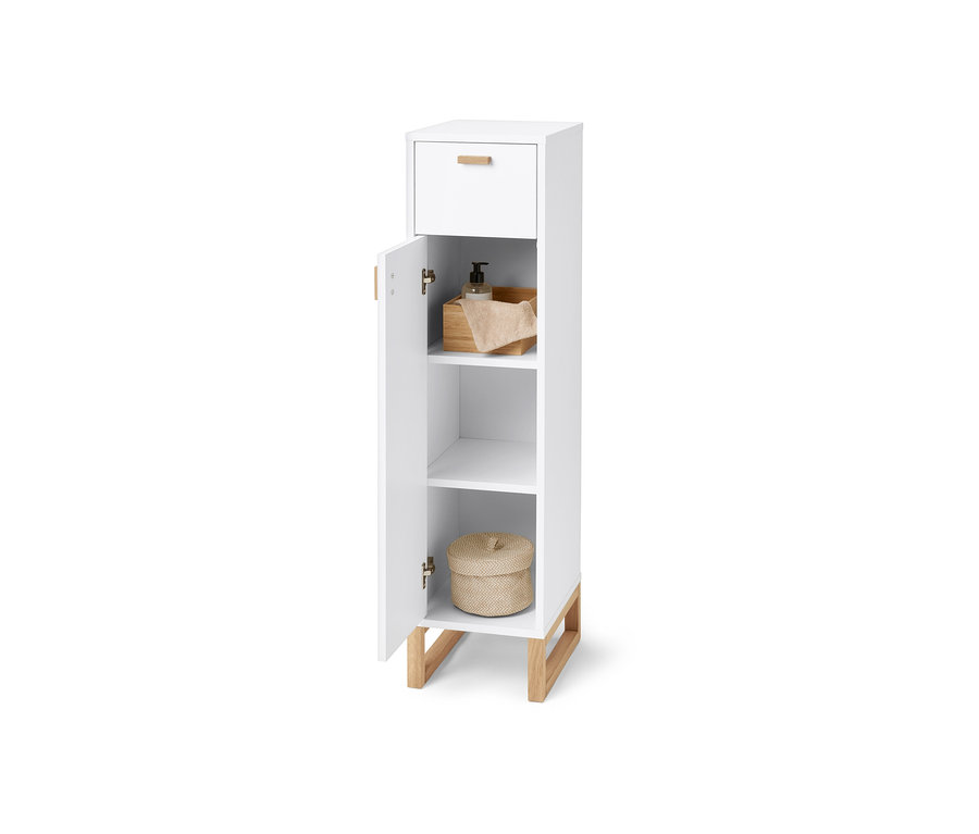 Armoire de salle de bain étroite avec tiroir et porte. À l'intérieur, il y a du savon, une serviette et un panier en osier.