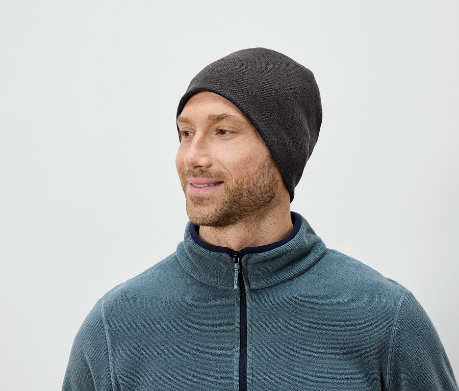 Homme barbu portant un bonnet gris et une polaire bleue regardant vers la droite.