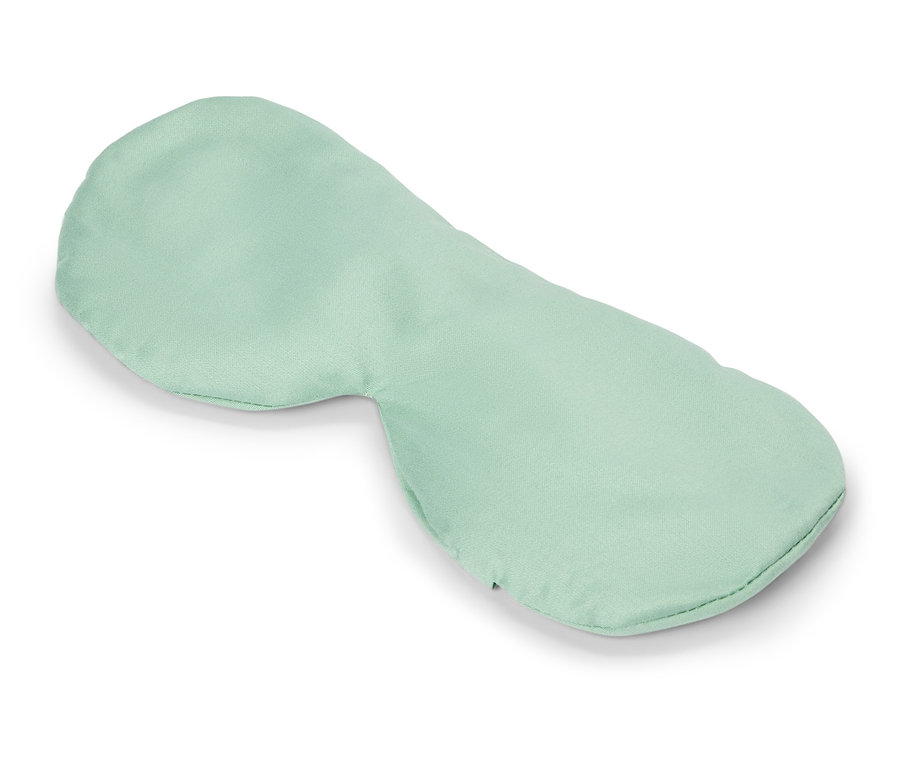 Un masque pour les yeux vert clair repose sur un fond blanc.