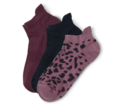 Trois chaussettes courtes sont superposées : une bordeaux, une noire et une mauve à taches noires.