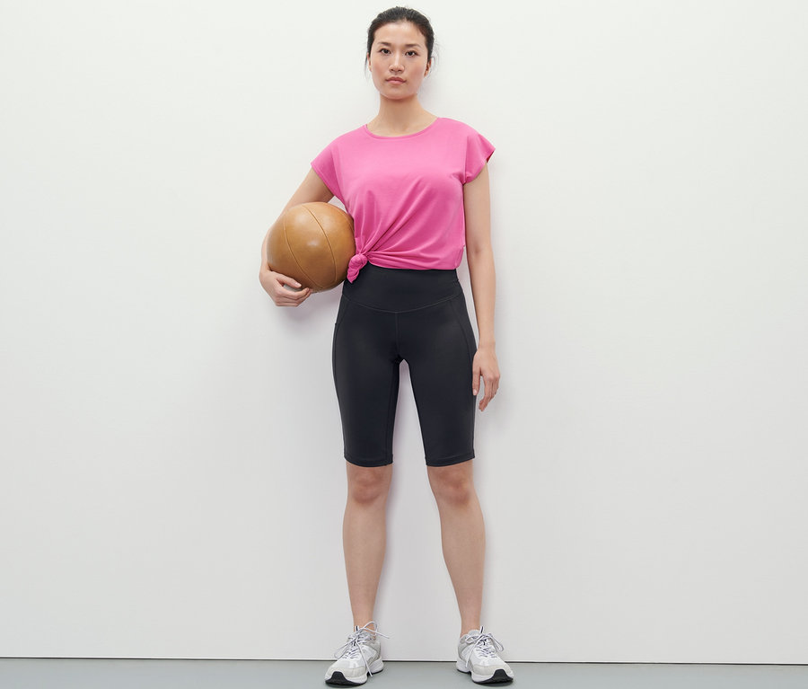 Femme tenant un ballon de médecine et portant un cycliste de sport.