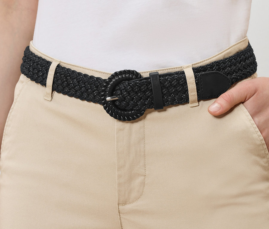 Ceinture tressée noire, aspect raphia, sur un pantalon beige.