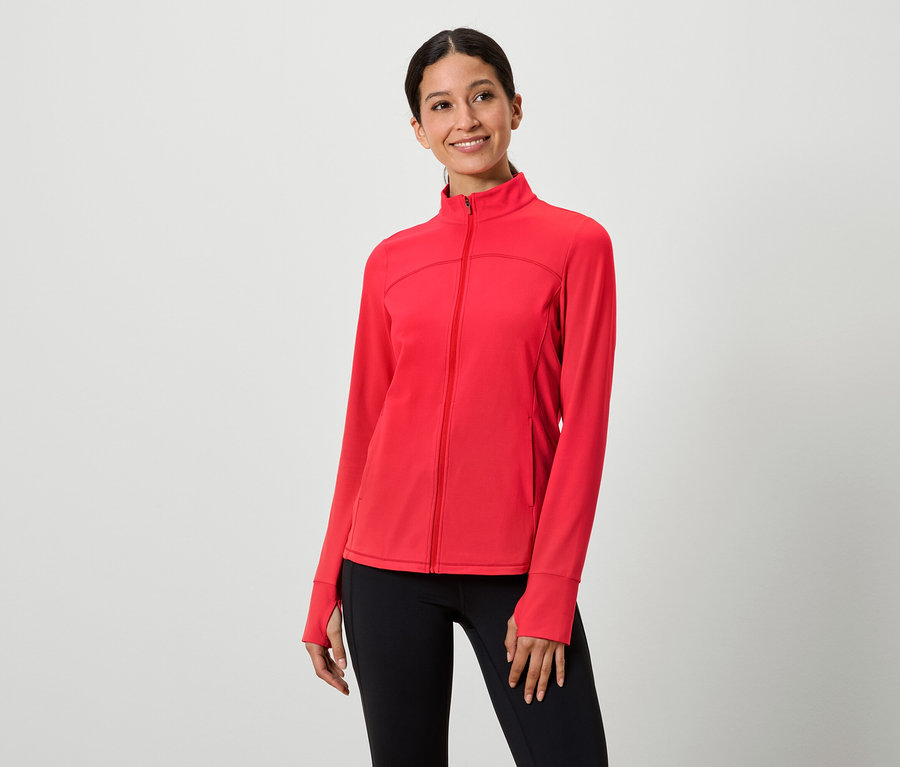 Une femme porte une veste rouge zippée et un legging noir.