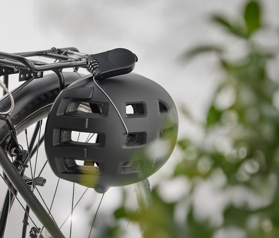 Un casque de vélo noir est suspendu à un porte-bagages de vélo avec un cadenas à combinaison.