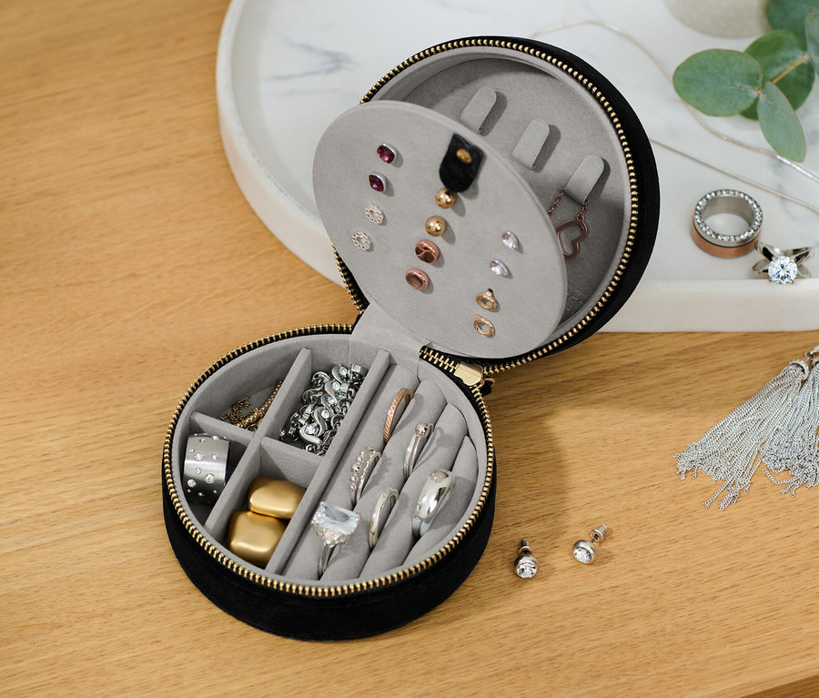 Une petite boîte à bijoux partiellement ouverte avec divers bijoux à l'intérieur.