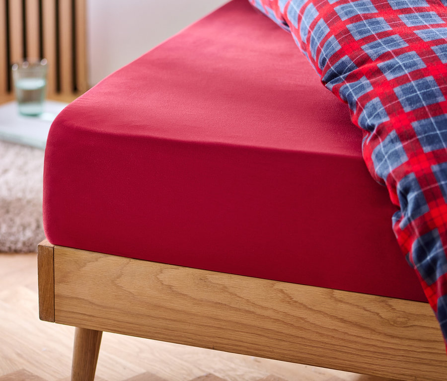 Drap-housse rouge en flanelle de microfibre sur un lit.