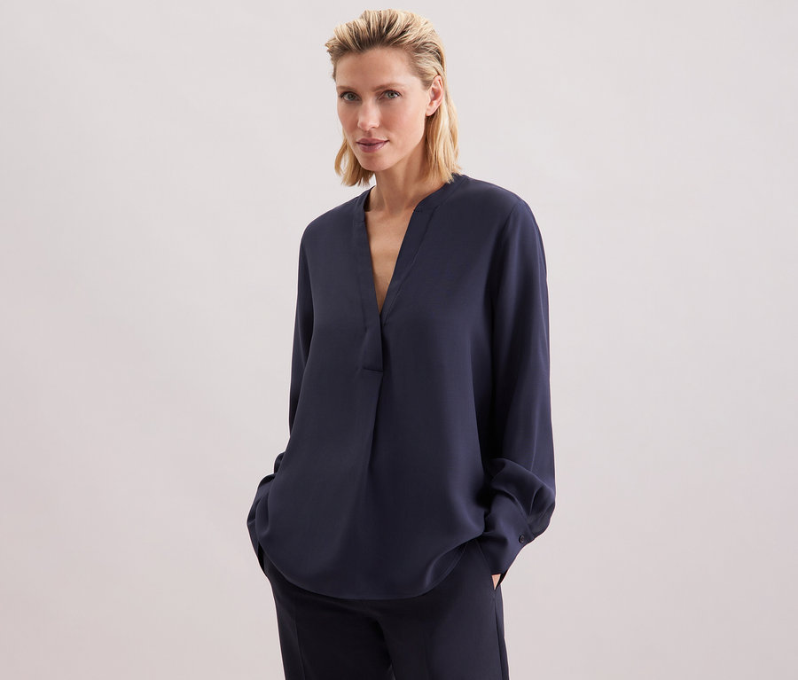 Femme portant une tunique en viscose Seidensticker bleu marine et un pantalon.