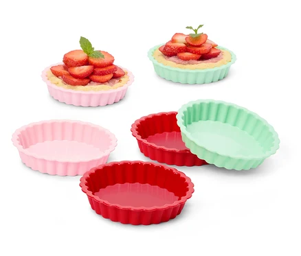 Plusieurs moules à tarte colorés, certains remplis de tartelettes aux fraises.