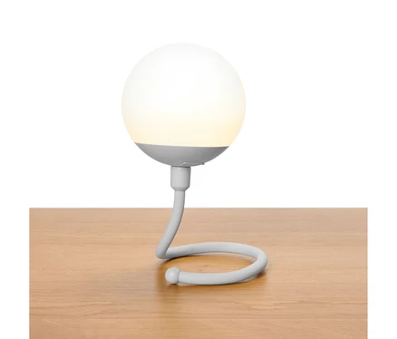 Lampe sphérique grise avec un col incurvé posée sur une table en bois.