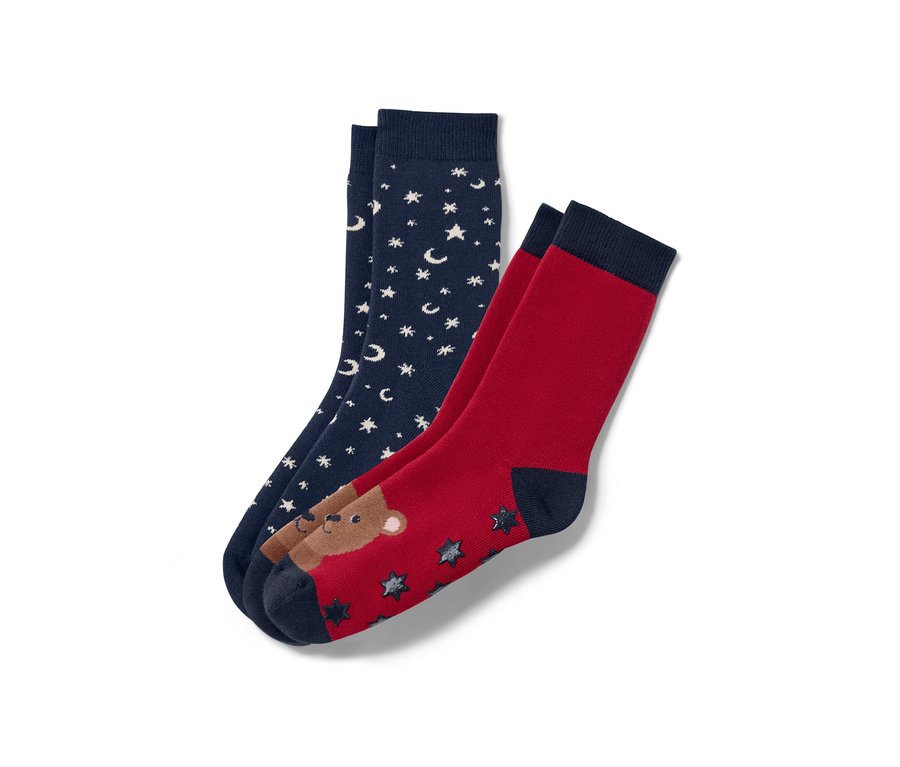 Deux paires de chaussettes antidérapantes pour enfant : une paire bleu marine avec des étoiles et des lunes blanches, une paire rouge avec un ours et des étoiles.