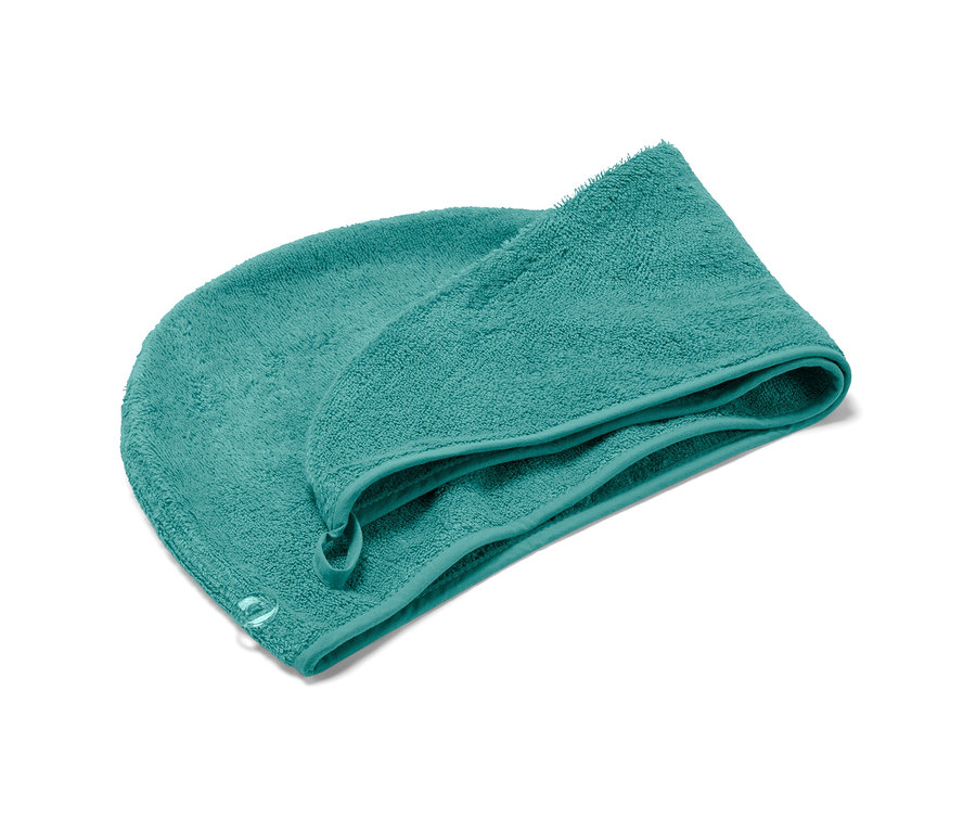 Une serviette turban turquoise est posée sur un fond blanc.
