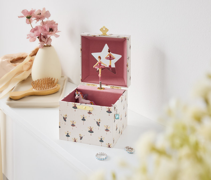 Boîte à musique ouverte avec ballerines et licorne sur une table blanche.