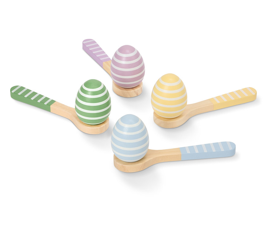 Quatre œufs de Pâques peints et rayés dans des couleurs pastel reposent sur de petites cuillères en bois.
