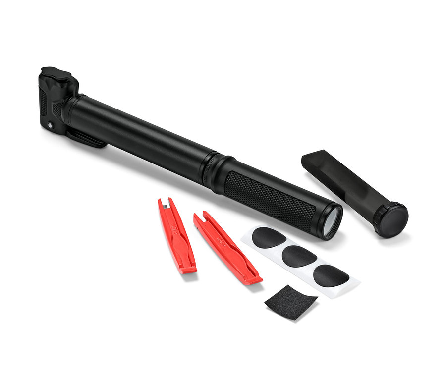 Une mini-pompe à vélo noire est posée à côté de deux démonte-pneus rouges, de rustines et de papier de verre.