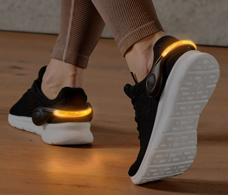 Jambes portant 2 clips pour chaussures à LED sur des chaussures noires.