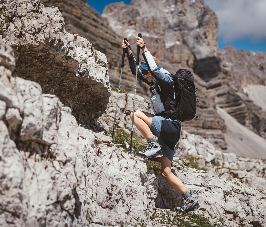 Femme grimpant sur des rochers avec des bâtons de trekking CMP et un sac à dos de trekking CMP HAVRE, 40 litres.