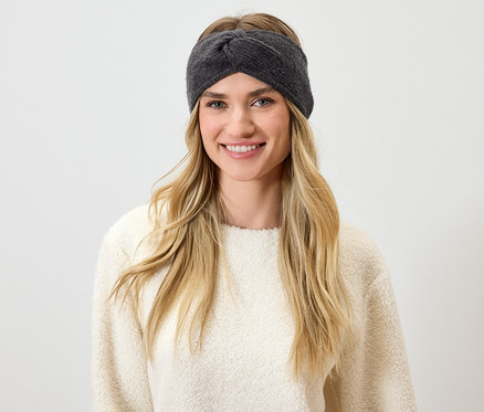 Une femme aux cheveux blonds et portant un bandeau gris sourit.