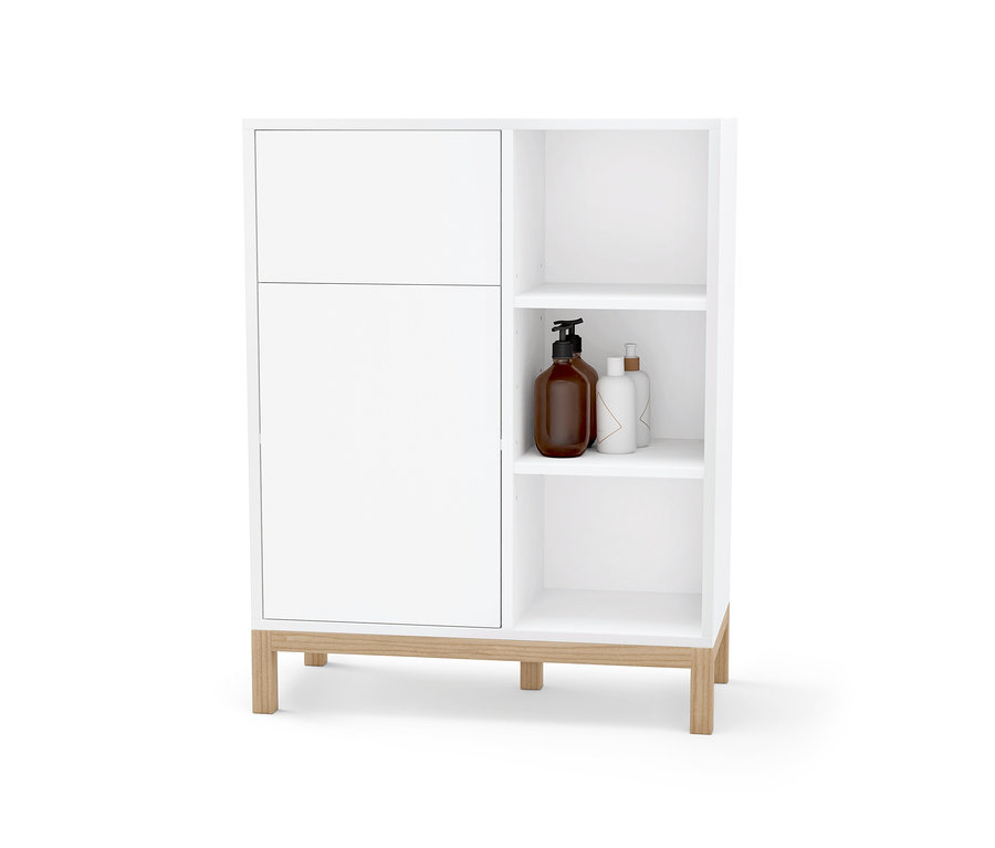 Meuble de salle de bain blanc avec porte et étagères ouvertes contenant des bouteilles.