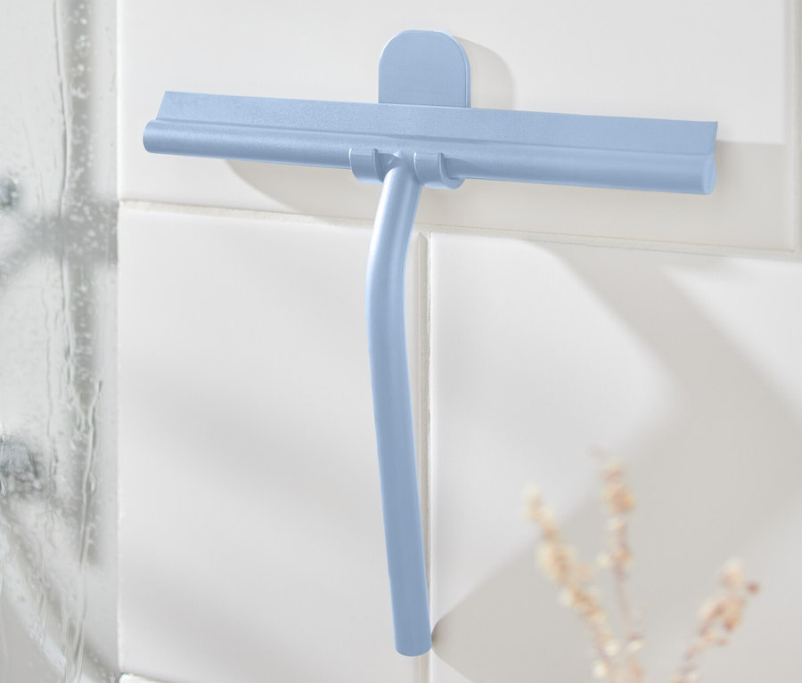 Raclette de salle de bain bleue avec support mural sur des carreaux blancs à côté de la douche.