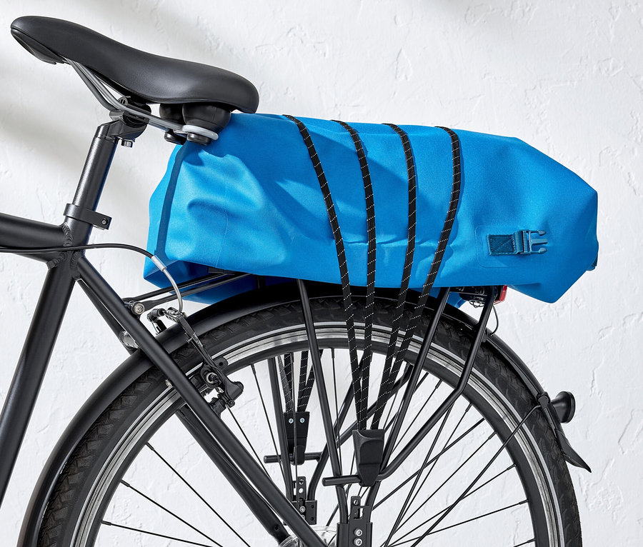 Gros plan de la roue arrière d'un vélo noir avec un sac de porte-bagages bleu.