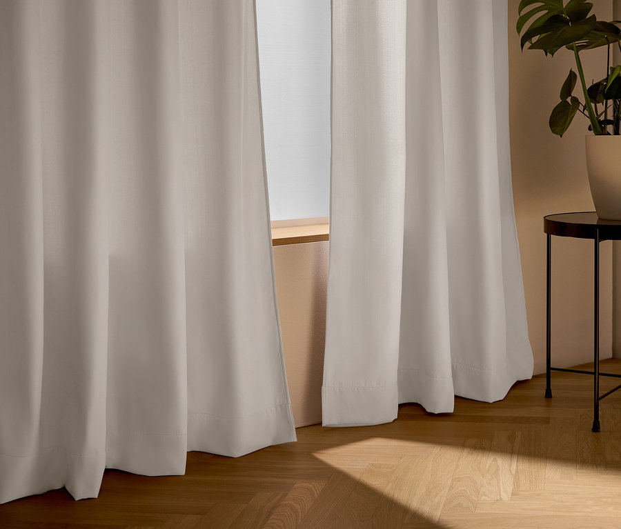 Rideaux beige devant une fenêtre, à côté d'une table avec une plante.