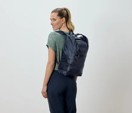 Femme blonde, vue de dos, portant un sac à dos bleu marine.