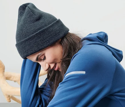 Une femme est assise et porte un bonnet en maille bleu.