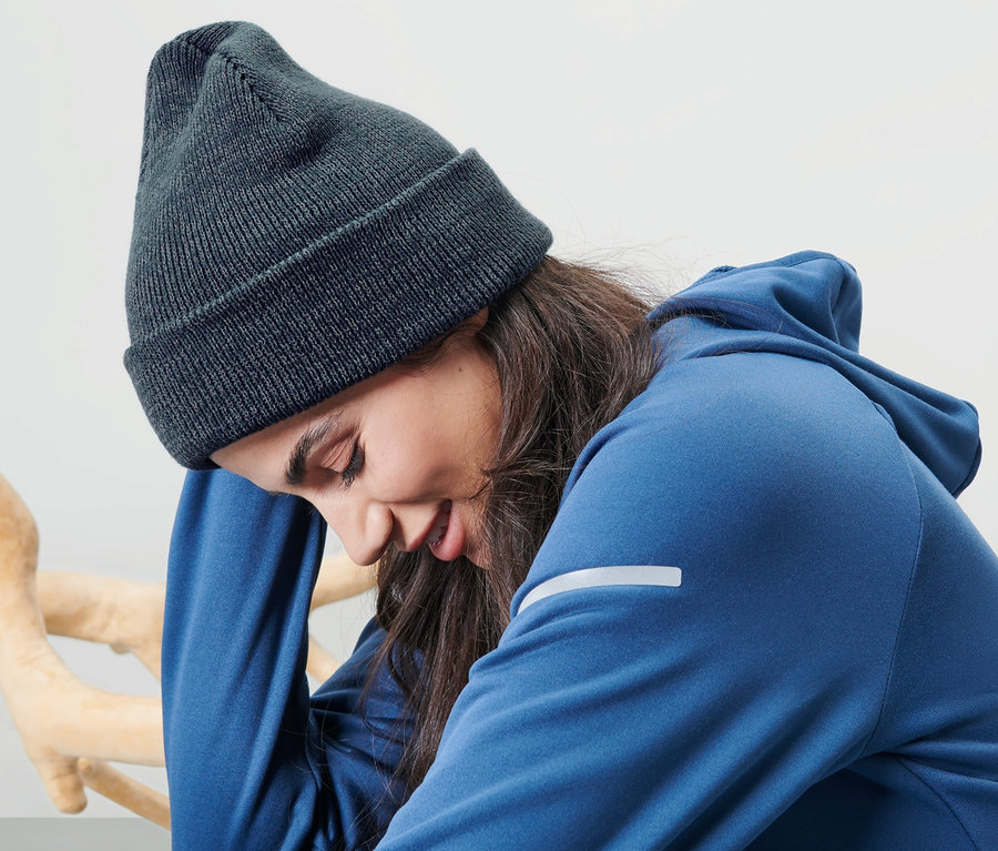 Une femme est assise et porte un bonnet en maille bleu.