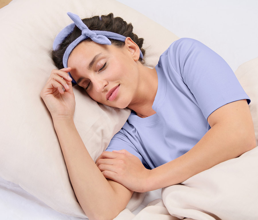 Une femme dort sur un oreiller avec un bandeau bleu sur la tête.