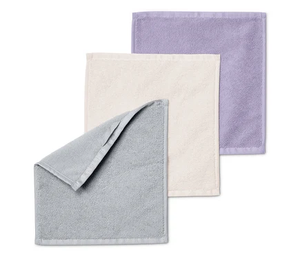 Trois serviettes pliées les unes sur les autres : grise, crème et violette.