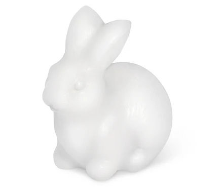 Une figurine de lapin blanche assise sur un fond blanc.