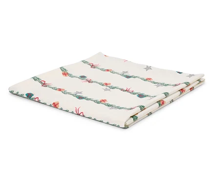 Nappe blanche pliée avec un motif de Noël de branches, de cadeaux et d'étoiles.