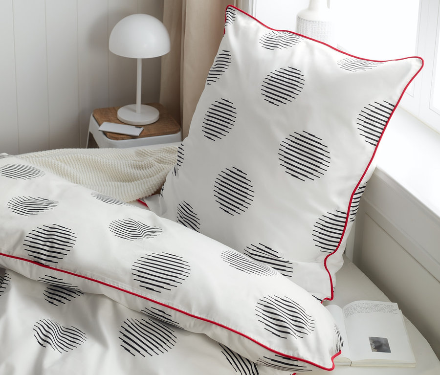 Gros plan sur une parure de lit en percale de taille standard, grande taille et taille double avec des cercles noirs et une bordure rouge.