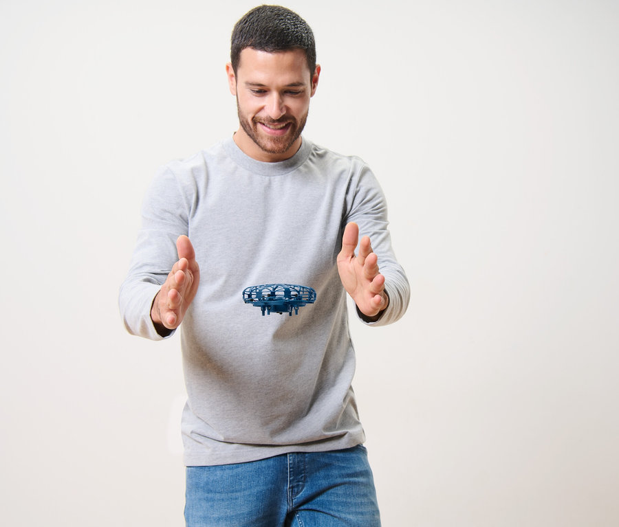 Un homme sourit en regardant un mini-drone « OVNI » voler entre ses mains.