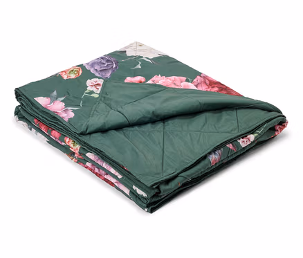 Couverture matelassée verte pliée avec un motif floral rose, violet et blanc.